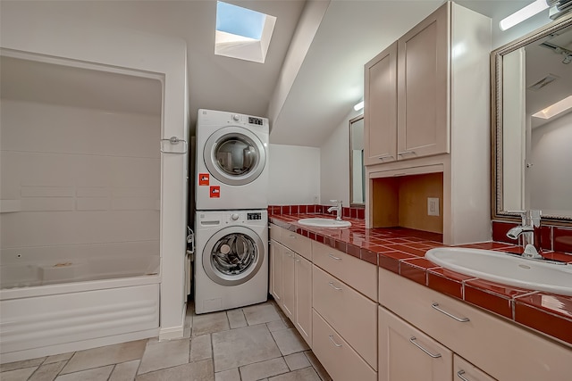 laundry room with sink, stacked washer / dryer, light tile patterned floors, and a skylight