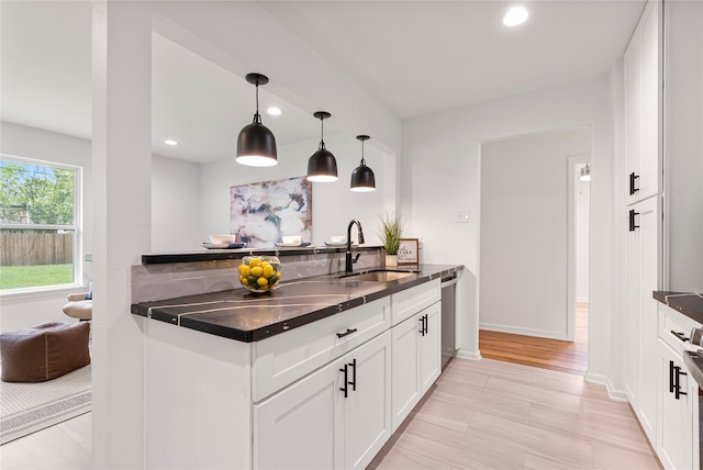 kitchen with decorative light fixtures, sink, white cabinetry, and stainless steel dishwasher