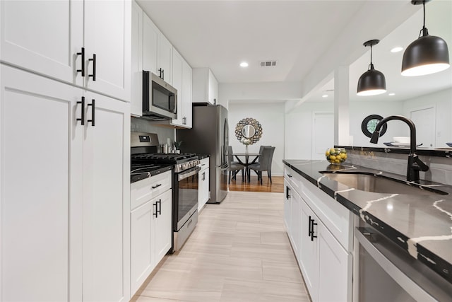 kitchen with sink, white cabinets, hanging light fixtures, and stainless steel appliances