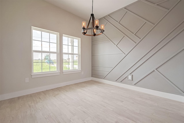 spare room with light wood-type flooring and a notable chandelier