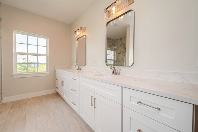 bathroom with tiled shower, wood-type flooring, and vanity