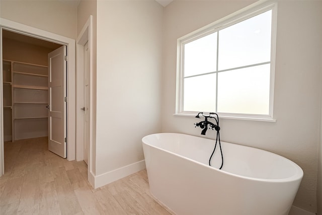 bathroom with a bath, hardwood / wood-style flooring, and a wealth of natural light