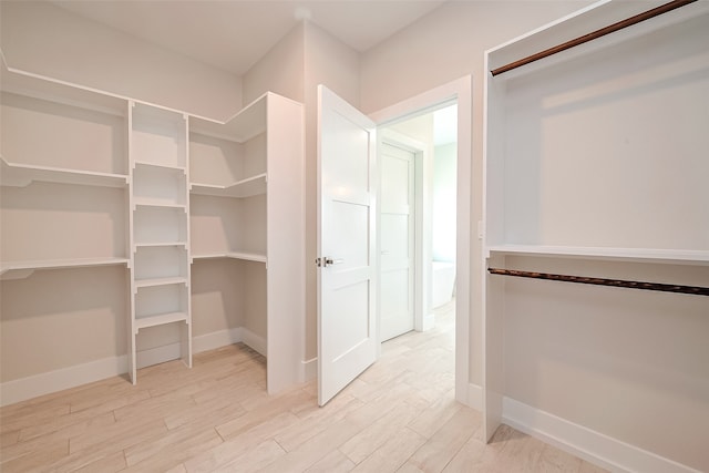 walk in closet with light hardwood / wood-style flooring