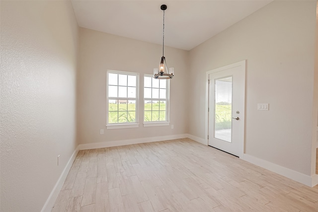 spare room featuring a notable chandelier and light hardwood / wood-style flooring