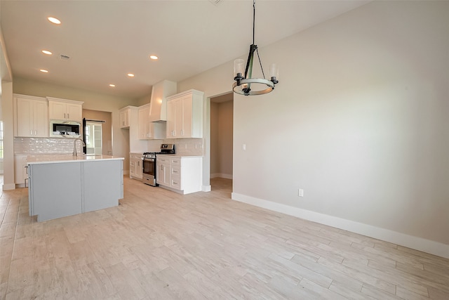 kitchen with white cabinetry, light hardwood / wood-style flooring, stainless steel appliances, and custom range hood