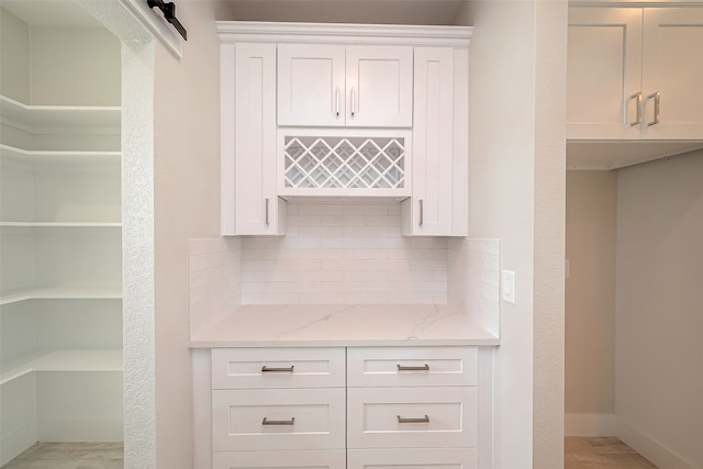 interior space featuring backsplash, a barn door, and white cabinets