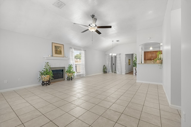 unfurnished living room with light tile patterned flooring, a tile fireplace, ceiling fan with notable chandelier, and vaulted ceiling