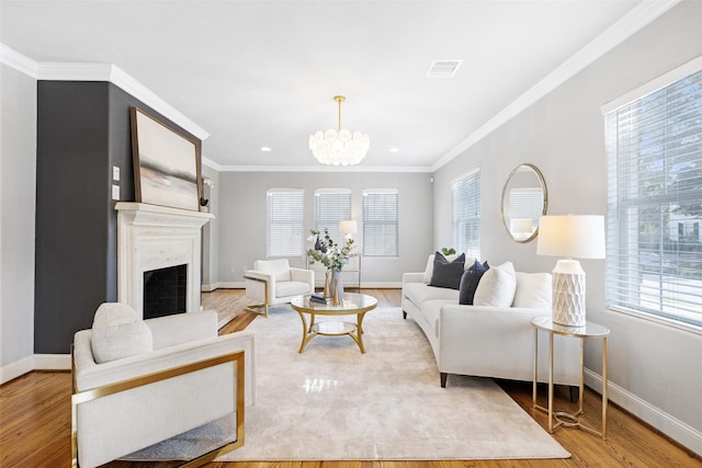 living room with crown molding, light wood-type flooring, a chandelier, and a wealth of natural light