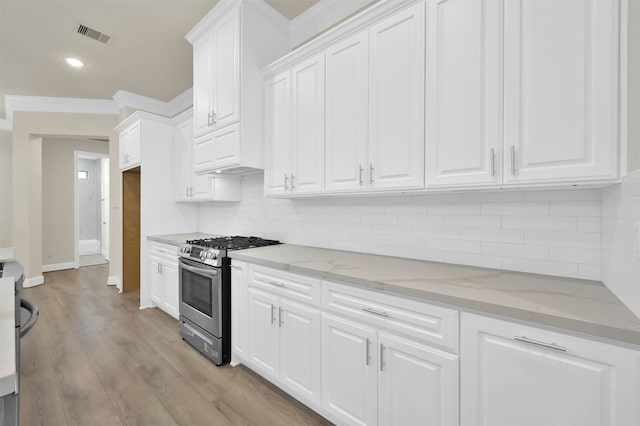 kitchen with backsplash, light wood-type flooring, stainless steel range with gas cooktop, white cabinets, and light stone counters