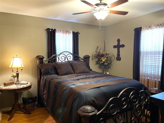 bedroom with ceiling fan, hardwood / wood-style flooring, and multiple windows