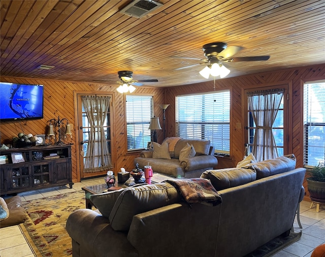 tiled living room with ceiling fan, wooden ceiling, wooden walls, and a healthy amount of sunlight