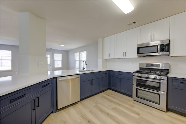 kitchen with appliances with stainless steel finishes, kitchen peninsula, white cabinets, and a wealth of natural light