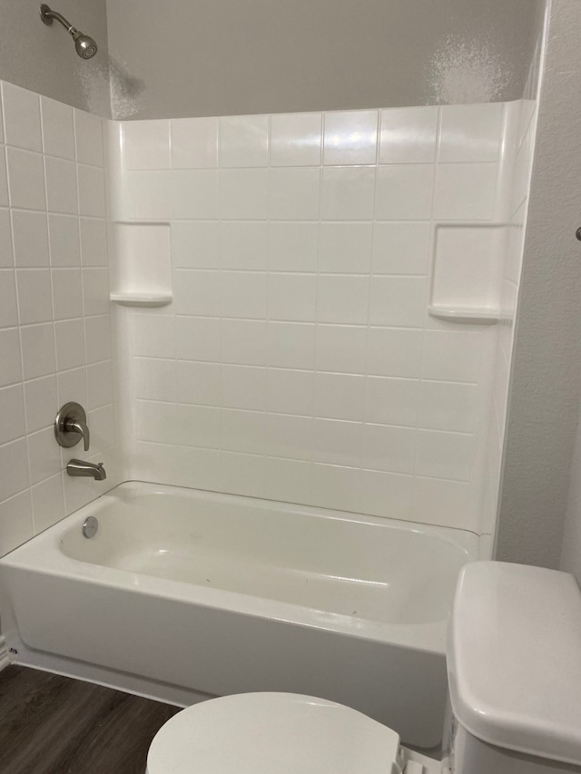 bathroom featuring toilet, tiled shower / bath, and wood-type flooring