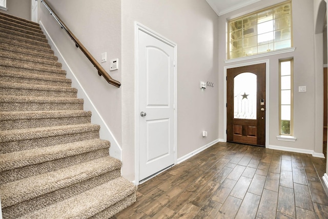 foyer entrance featuring dark hardwood / wood-style floors, a towering ceiling, and crown molding