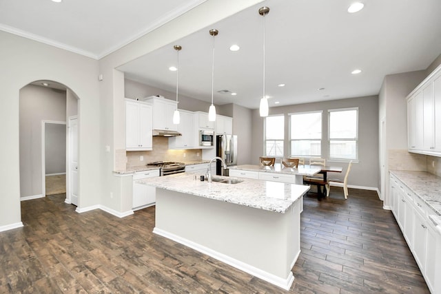 kitchen featuring white cabinets, pendant lighting, and a center island with sink