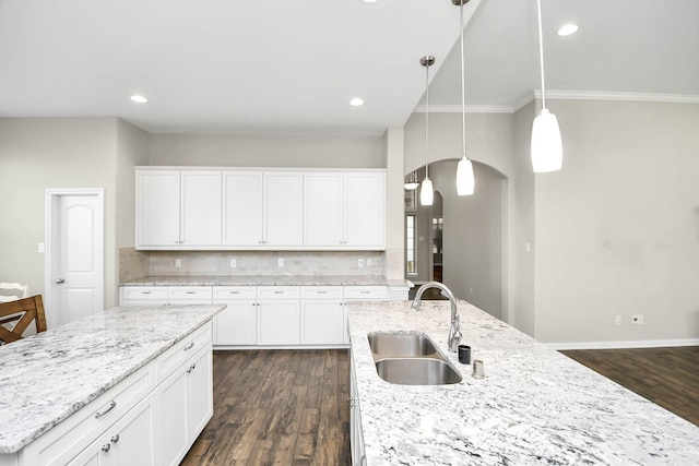 kitchen featuring pendant lighting, a kitchen island with sink, dark wood-type flooring, sink, and white cabinetry