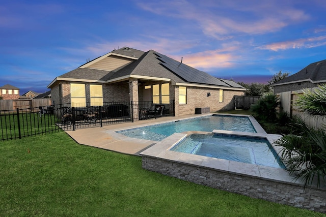 pool at dusk featuring a patio area, a yard, an in ground hot tub, and central air condition unit