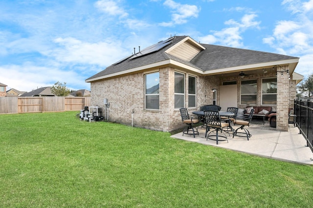 rear view of house with outdoor lounge area, solar panels, ceiling fan, a yard, and a patio area