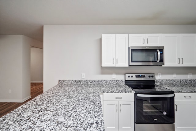 kitchen featuring white cabinetry, light stone countertops, appliances with stainless steel finishes, and dark wood-type flooring