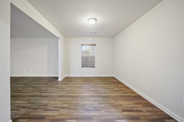 spare room with a textured ceiling and dark hardwood / wood-style floors