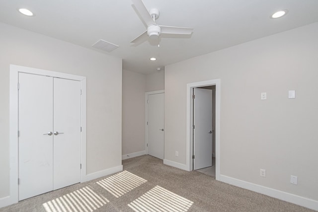 unfurnished bedroom featuring a closet, light colored carpet, and ceiling fan