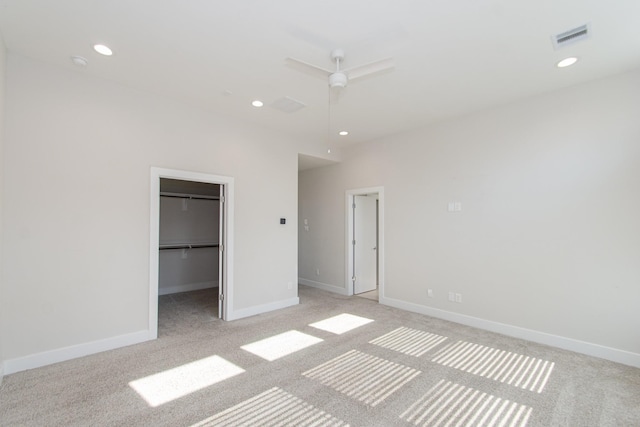 unfurnished bedroom featuring a spacious closet, ceiling fan, a closet, and light colored carpet