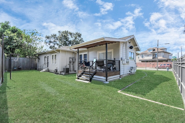 rear view of property with a yard, a deck, and central AC unit