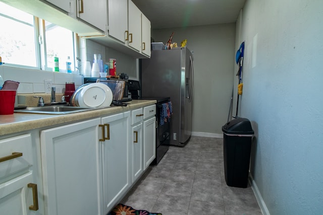 kitchen featuring stainless steel fridge, sink, and white cabinetry