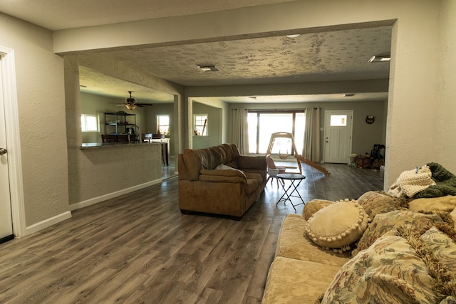 living room featuring dark hardwood / wood-style floors, beamed ceiling, and ceiling fan