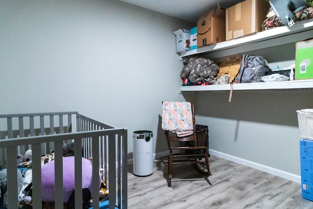 bedroom featuring light hardwood / wood-style flooring and a nursery area