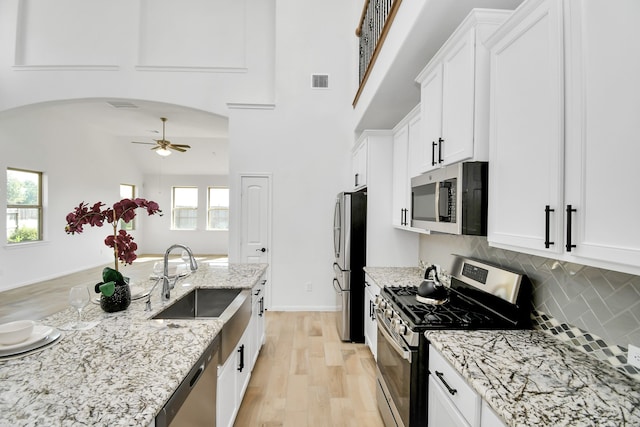 kitchen with light hardwood / wood-style flooring, sink, light stone countertops, white cabinets, and appliances with stainless steel finishes