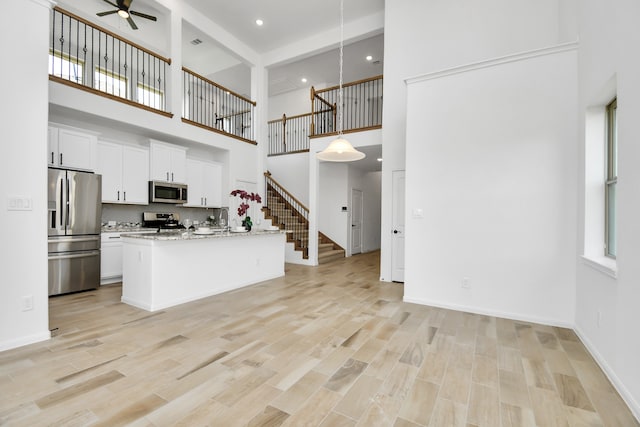 kitchen featuring white cabinets, stainless steel appliances, and a high ceiling