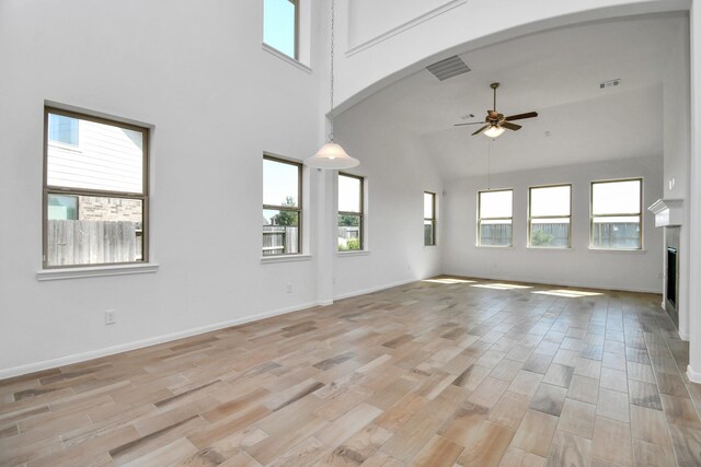 unfurnished living room featuring high vaulted ceiling, light wood-type flooring, and a healthy amount of sunlight