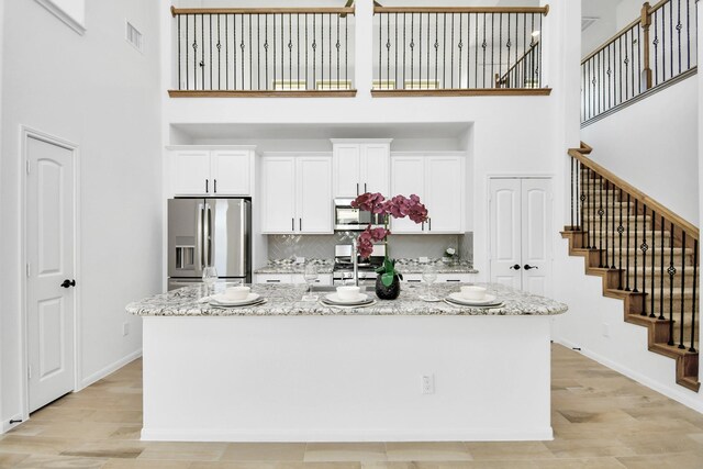 kitchen featuring appliances with stainless steel finishes, light stone countertops, a center island, and a towering ceiling