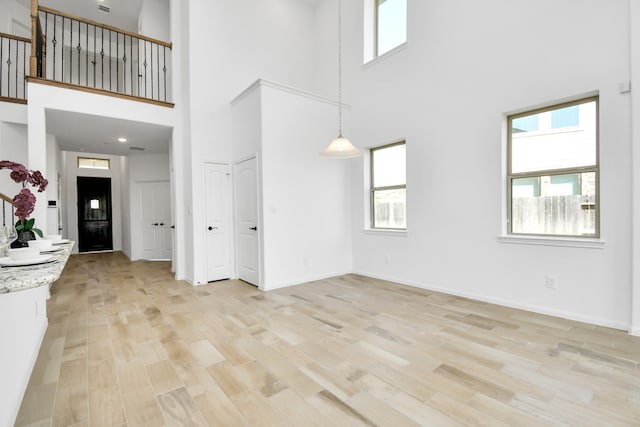 unfurnished living room featuring a high ceiling and light wood-type flooring