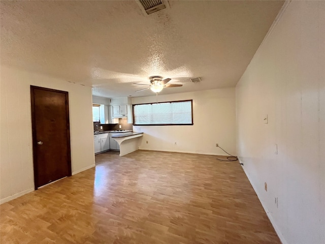 unfurnished room with a textured ceiling, light hardwood / wood-style floors, and ceiling fan