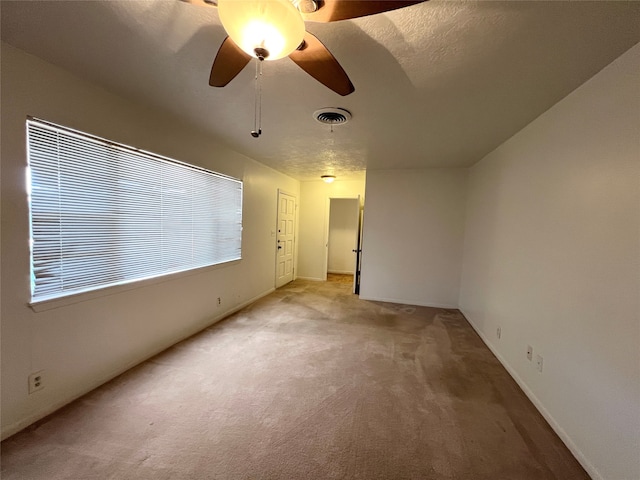 unfurnished room featuring a textured ceiling, light colored carpet, and ceiling fan