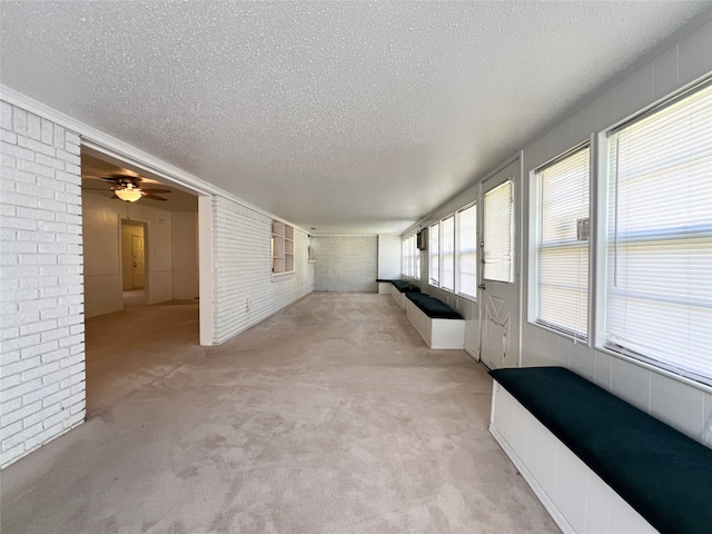 unfurnished sunroom featuring ceiling fan and a wealth of natural light