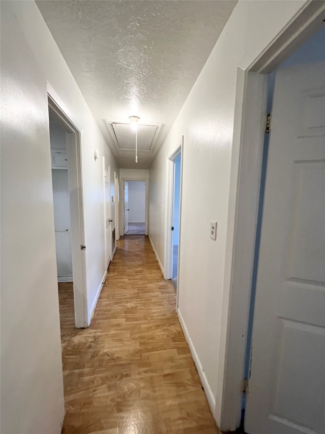 hallway featuring light hardwood / wood-style flooring and a textured ceiling