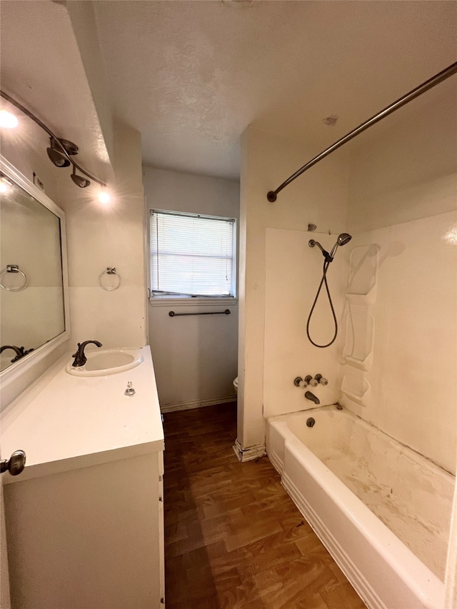 full bathroom with a textured ceiling, hardwood / wood-style floors, toilet, vanity, and shower / bathtub combination