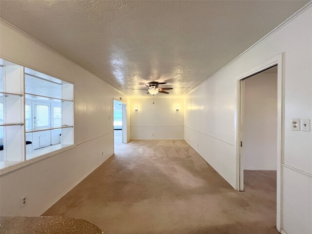 carpeted empty room featuring crown molding, a textured ceiling, and ceiling fan