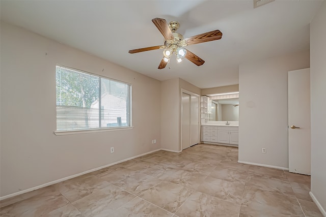 unfurnished bedroom featuring connected bathroom, ceiling fan, and sink