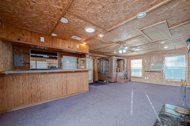 kitchen with wood walls, kitchen peninsula, light brown cabinets, and electric panel