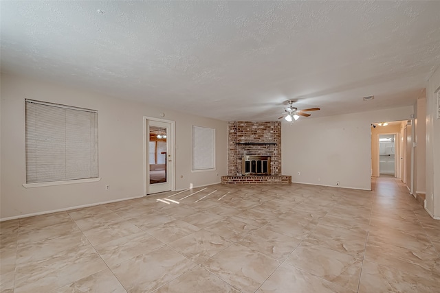 unfurnished living room with a textured ceiling, a brick fireplace, and ceiling fan