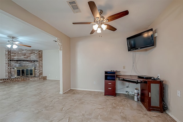 unfurnished living room with ceiling fan and a brick fireplace