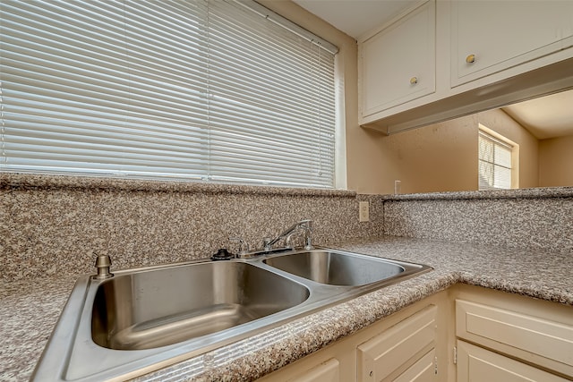 kitchen with cream cabinets, backsplash, and sink