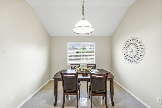 tiled dining space featuring vaulted ceiling