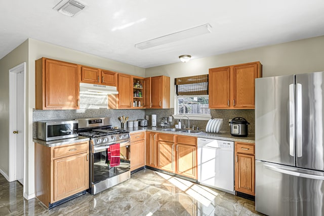 kitchen featuring appliances with stainless steel finishes, light stone counters, sink, and tasteful backsplash