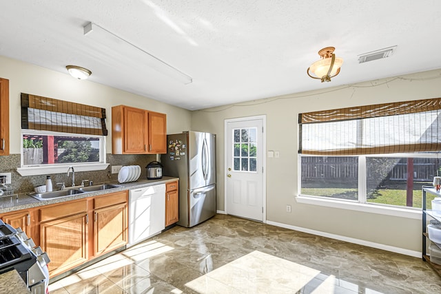 kitchen with stainless steel appliances, decorative backsplash, sink, and a textured ceiling