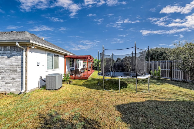 view of yard with a trampoline, central air condition unit, and a deck